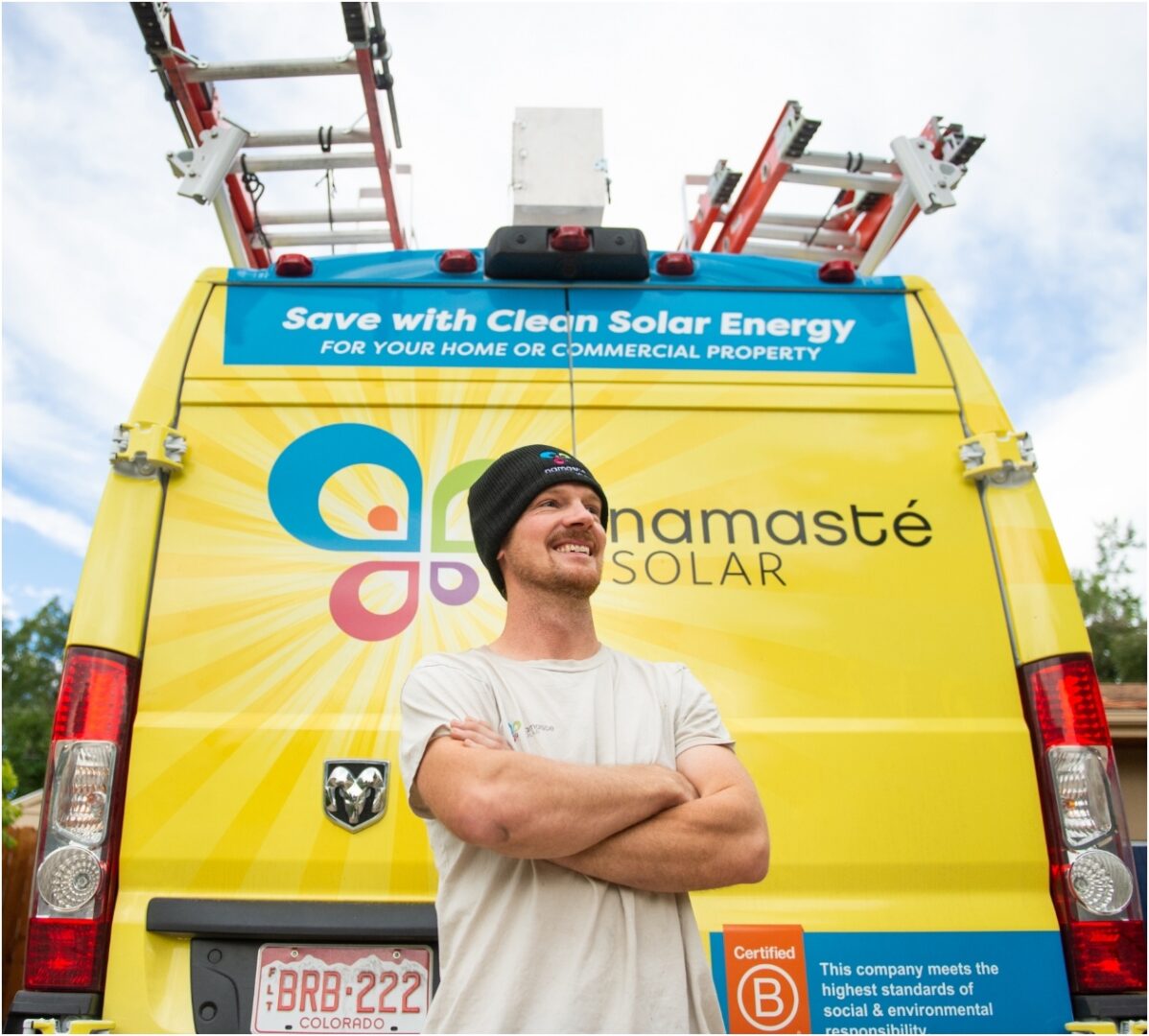 Employee standing in front of yellow Namaste Solar truck.