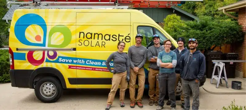 Namaste Solar group of co-owners in front of yellow truck.